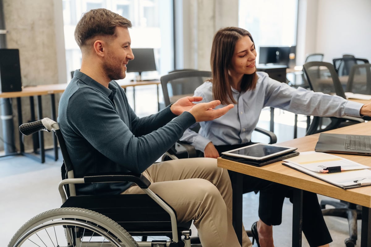 NDIS Plan Manager Meadow Heights - Man in wheelchair talking with woman at desk in contemporary office